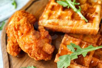 Delicious waffles with chicken and honey on wooden board, closeup�