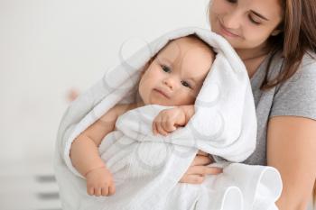 Young woman with cute little baby wrapped in soft towel at home�