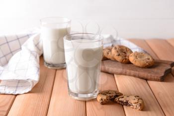 Glasses of tasty milk and cookies on wooden table�