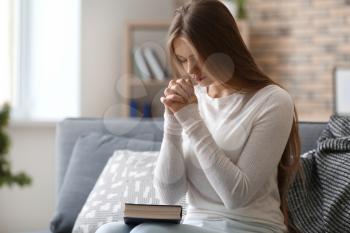 Beautiful young woman praying at home�