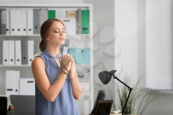Beautiful young woman praying in office�