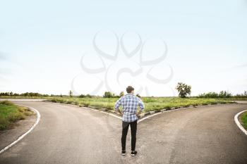 Young man standing at crossroads. Concept of choice�