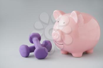 Piggy bank with dumbbells on light background. Weight loss concept�