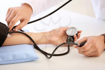 Male doctor measuring blood pressure of female patient in hospital�