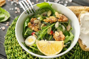 Delicious fresh salad with walnuts in bowl on table�