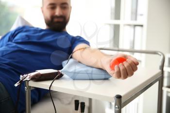 Man with grip ball donating blood in hospital�