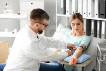 Male doctor preparing female donor for blood transfusion in hospital�