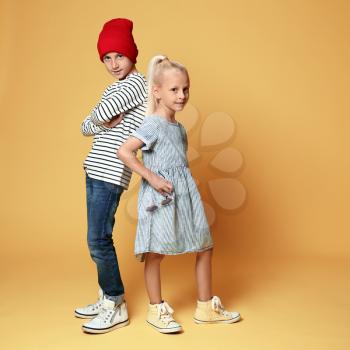 Cute boy and girl in fashionable clothes on color background�