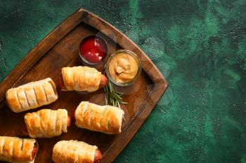 Wooden board with delicious sausage rolls on table�