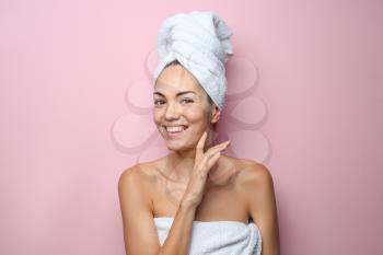 Beautiful young woman wrapped in towel on color background�