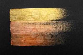 Strokes of different gold paints on dark background�