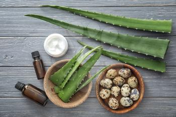 Fresh aloe leaves with cosmetic products and eggs on wooden table�