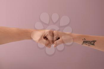 Man and woman making fist bump gesture on color background�