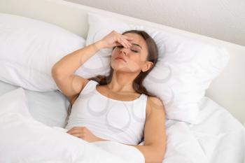 Woman suffering from headache in bedroom�