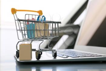 Small cart and laptop on table. Internet shopping concept�