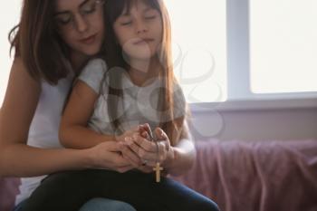 Mother with daughter praying at home�