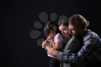 Praying family on dark background�