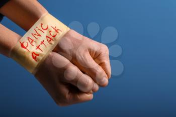 Tape with words PANIC ATTACK around male hands on color background�