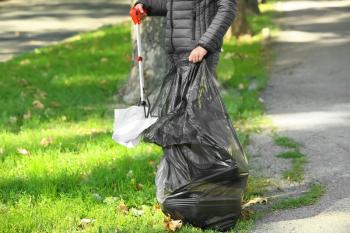 Woman gathering trash in park�