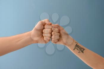 Man and woman bumping fists on color background�