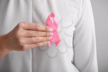 Woman holding pink ribbon, closeup. Breast cancer awareness concept�