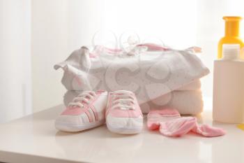 Baby clothes, shoes and cosmetics on table�