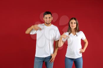 Young man and woman in stylish t-shirts on color background�