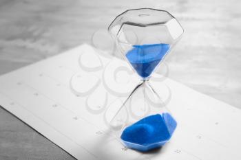 Crystal hourglass with blue sand on calendar�