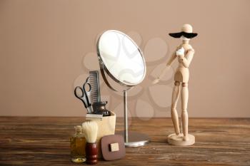 Funny small mannequin with mustache and foam in front of mirror on wooden table�