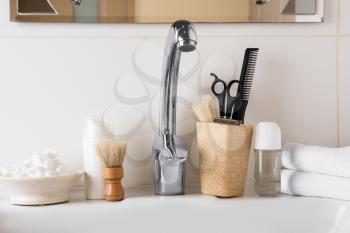 Shaving accessories with cosmetics for men on sink in bathroom�