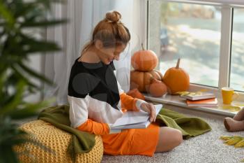 Woman reading book at home on autumn day�