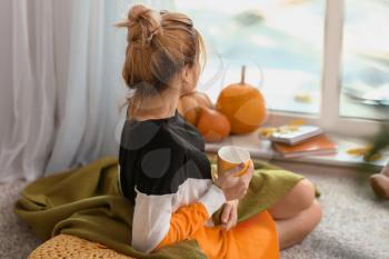 Woman drinking tea while resting at home on autumn day�