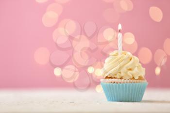 Delicious birthday cupcake with burning candle against blurred lights�