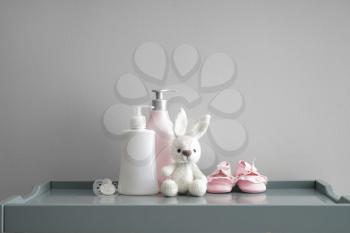 Bunny toy with shoes, pacifier and cosmetics for baby on grey table�