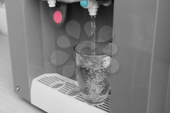 Filling of glass from water cooler, closeup�