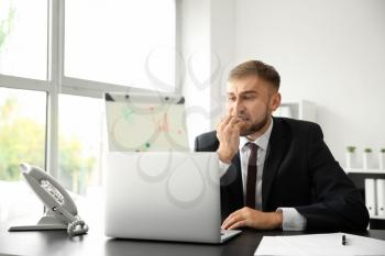 Emotional young businessman after making mistake while working with laptop in office�