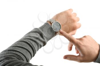 Young man pointing at his watch on white background�