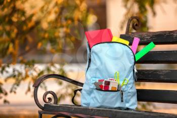 Color rucksack with school stationery on bench outdoors�