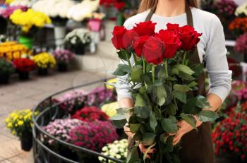 Saleswoman holding bouquet of beautiful roses in shop�