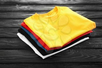 Stack of colorful t-shirts on wooden background�