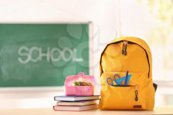 Backpack with school supplies and lunch box on table�
