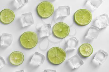Fresh sliced ripe lime and ice cubes on white background�