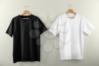 Hangers with blank t-shirts on light background�