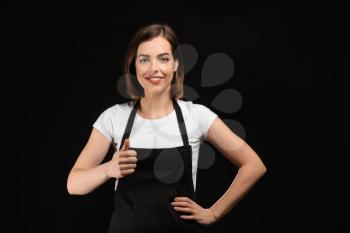 Young female chef on dark background�