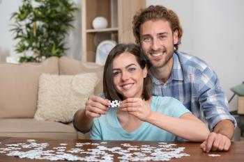 Young couple doing jigsaw puzzle at home�