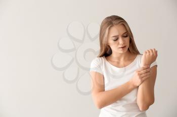 Young woman suffering from pain in wrist on light background�