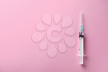 Syringe with liquid on color background�