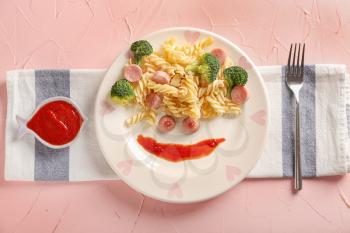 Plate with sausages, pasta and sauce for child on color table�