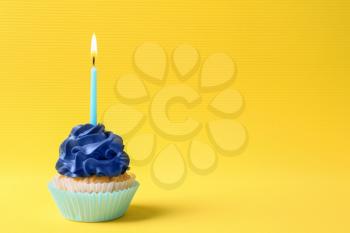Tasty cupcake with burning candle on color background�