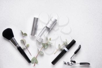 Cosmetics with makeup accessories on light background�